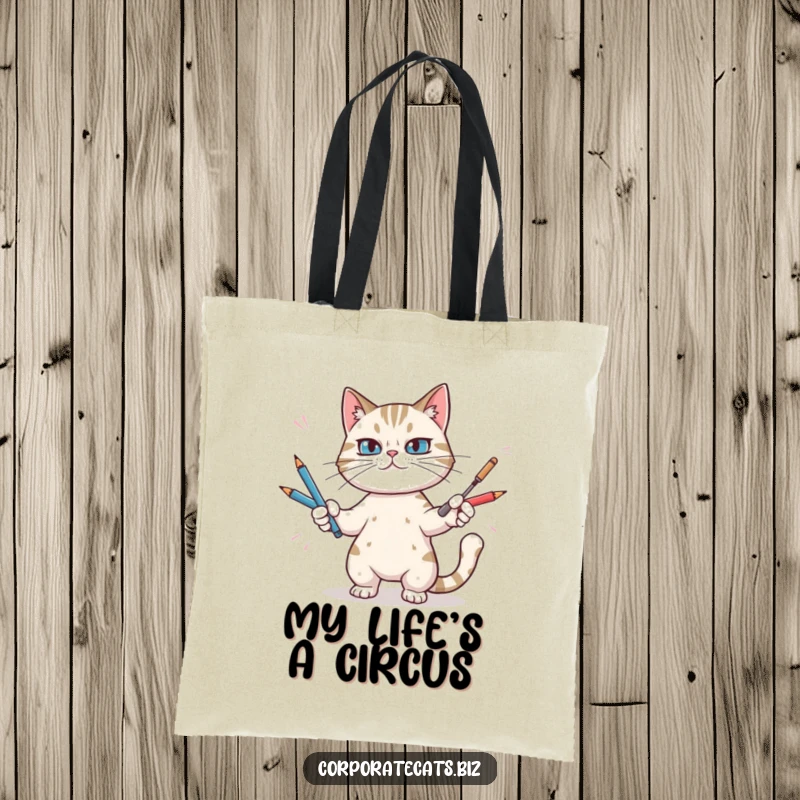 Funny tote bag illustrating a focused cat juggling an assortment of writing pens, a humorous take on daily tasks.